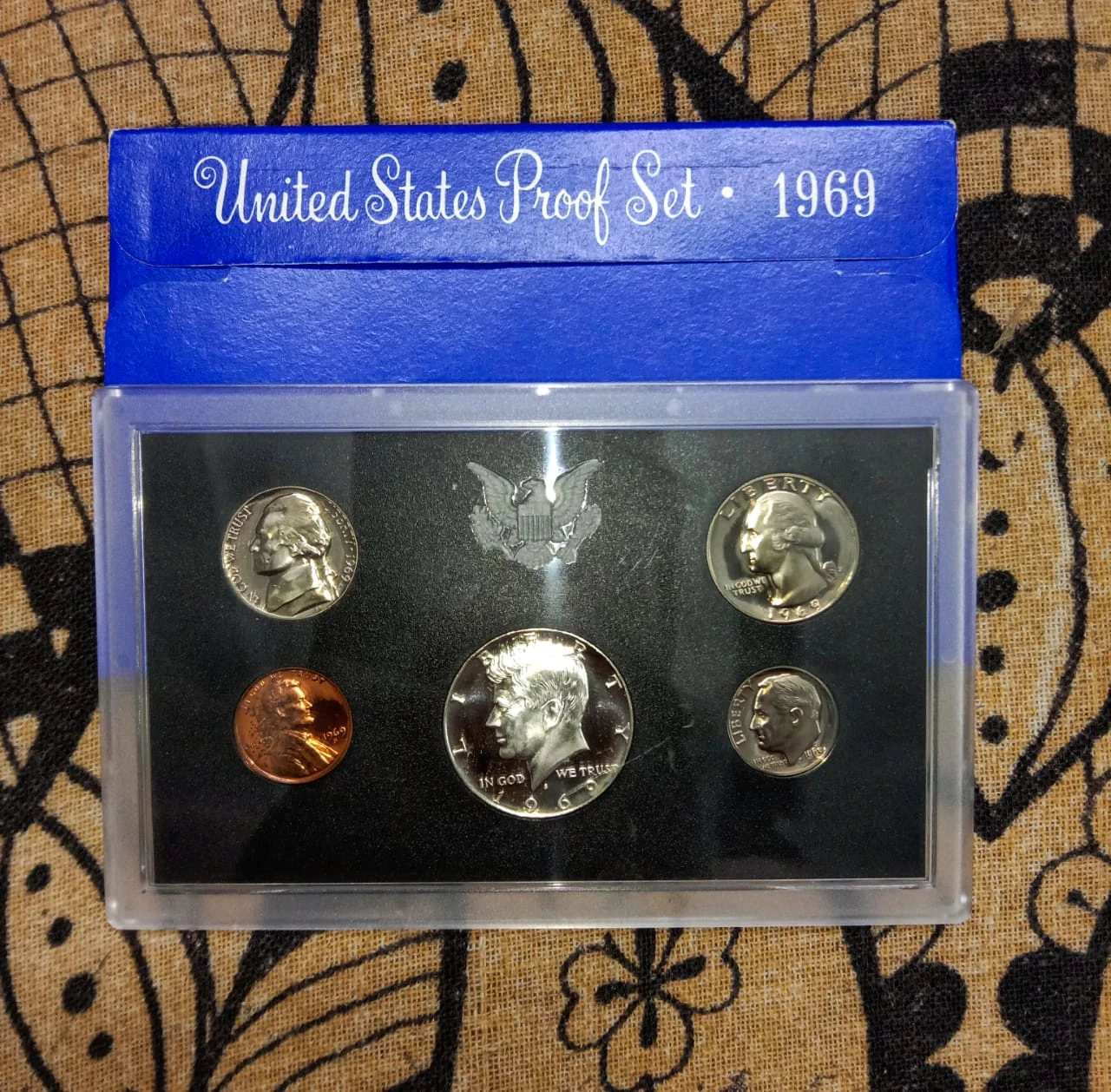 A 1969 United States Proof Set in its original presentation case beside its blue packaging.